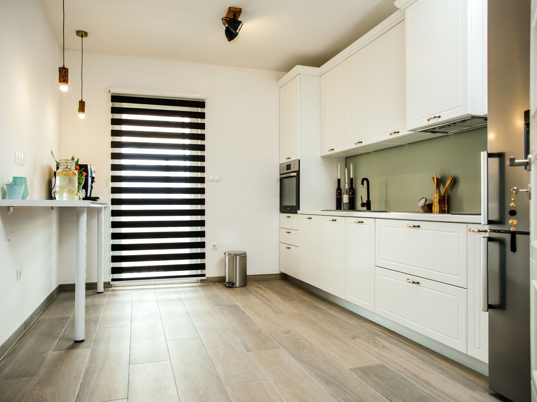 A modern kitchen with white cabinets, a stainless steel oven, and a black countertop.