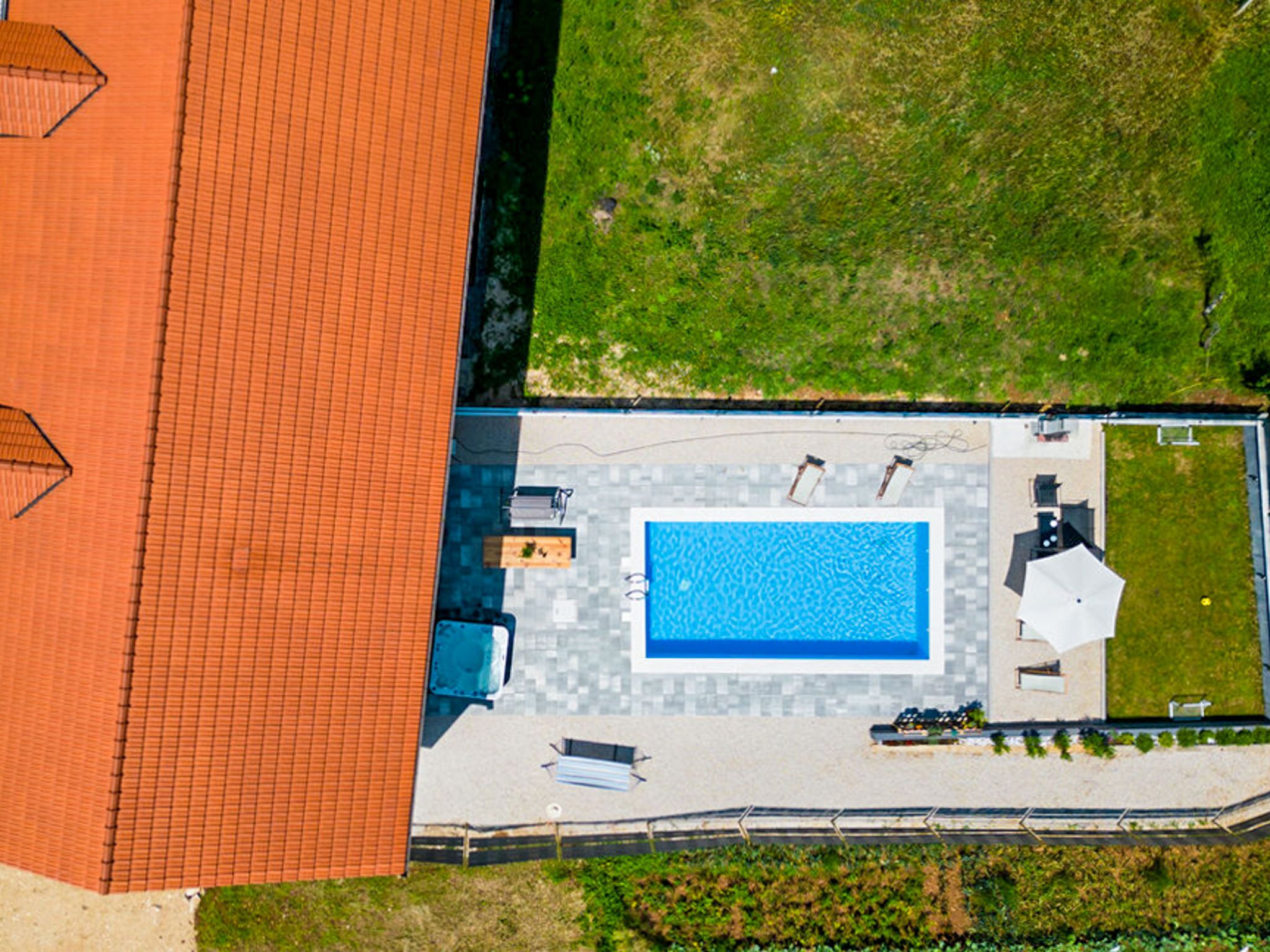 Vista aèria d'una propietat amb piscina, mobiliari exterior i zona tancada per una tanca.