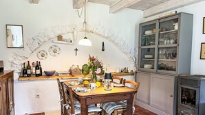 Een rustieke keuken met een houten eettafel, stoelen en een inbouwkast met glazen deuren.