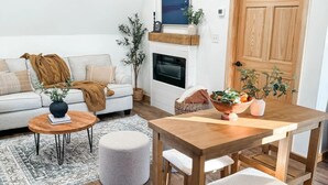 Un salon moderne avec un canapé, une table basse et une table à manger en bois, accompagnée de chaises.