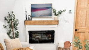 Un salon chaleureux avec une cheminée, un canapé, une table basse et un tapis.