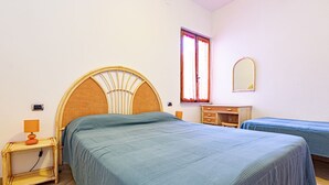 A bedroom with a large bed, a smaller bed, a nightstand, a dresser, a mirror, and a window with curtains. - Casa Bartolomea - CASA BARTOLOMEA 11 (Marina di Campo)