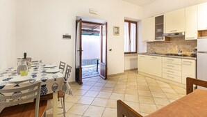 A compact kitchen with white cabinets, a dining table with chairs, and a view to an outdoor area. - Casa Bartolomea - CASA BARTOLOMEA 11 (Marina di Campo)