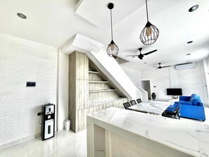 Experience a spacious, well-lit space with a staircase, flat-screen TV, and comfortable seating area.