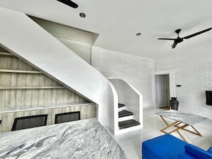 Stunning spiral staircase leads to a cozy seating area with a marble table and plush bench.