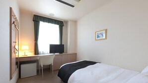 A hotel room with a bed, a desk with a computer, a chair, and a small refrigerator. - HOTEL LiVEMAX Numata GRANDE (Numata)