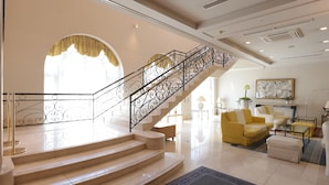 A spacious living area with a staircase, yellow and white furniture, and a large window with curtains. - HOTEL LiVEMAX Numata GRANDE (Numata)