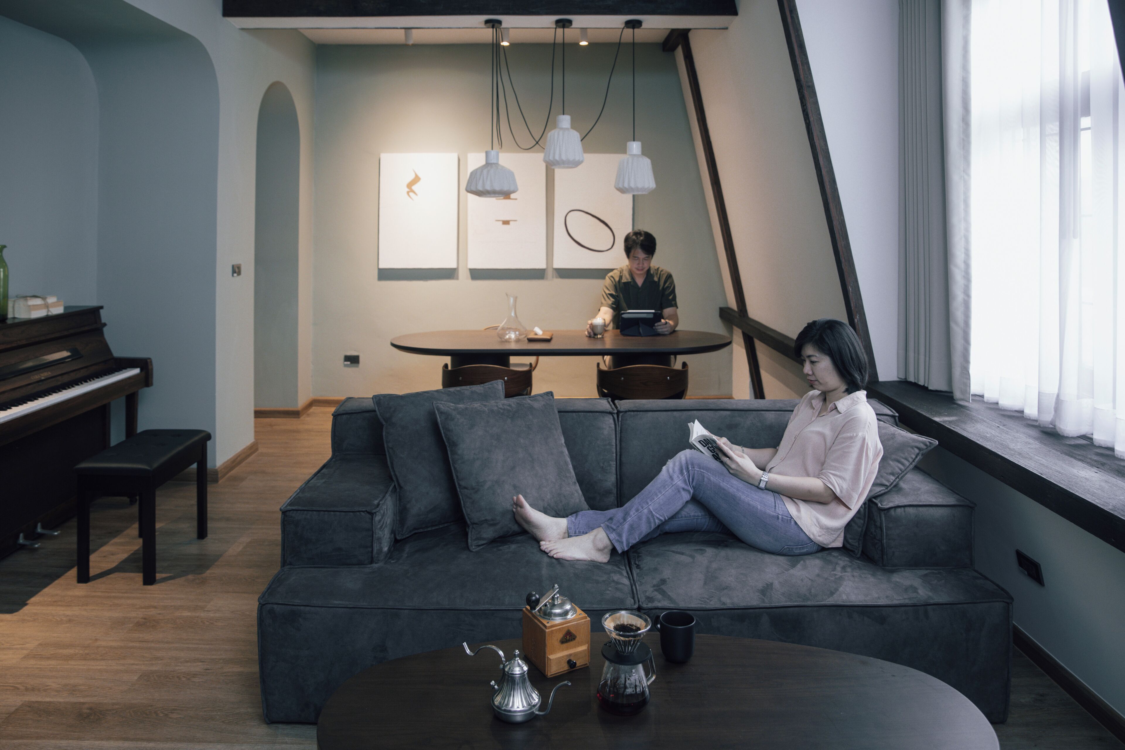 Ein modernes Wohnzimmer mit einer Couch, einem Couchtisch, einem Klavier und einem Esstisch.