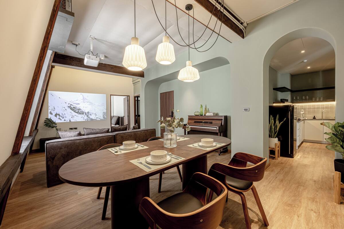 A modern dining area with a wooden table, four chairs, and a large window overlooking a snowy landscape.