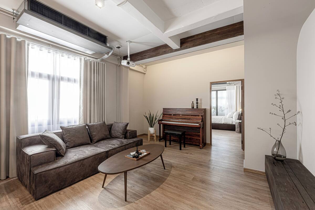 A modern living room with a sofa, coffee table, and a piano.