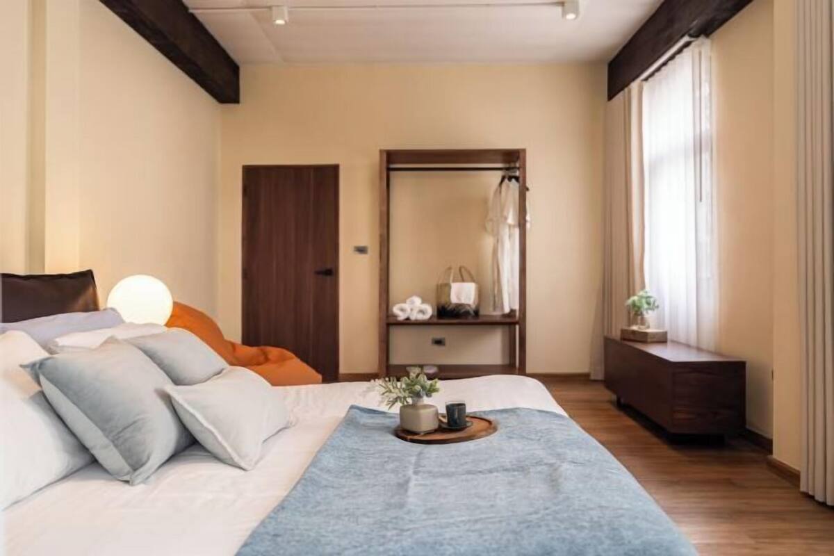 A bedroom with a bed, bedside table, and a mirror.