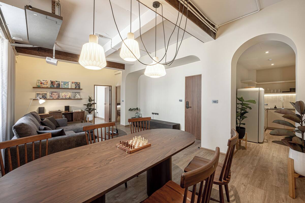 A spacious living area with a wooden dining table, comfortable seating, and a chessboard.