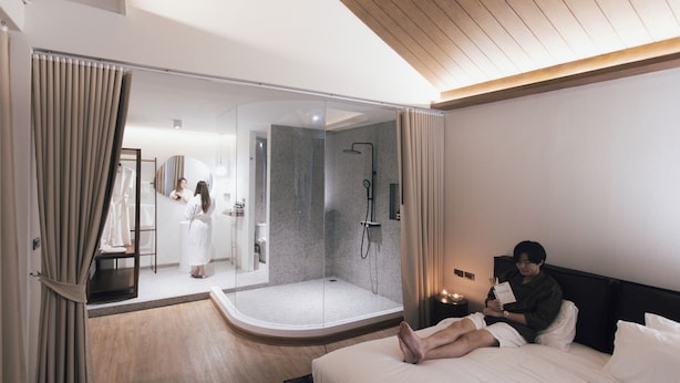 A modern hotel room with a large bed, a walk-in closet, and a glass-enclosed shower area. - The Lair Bangkok (Bangkok)