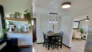 A modern kitchen with a wooden countertop, a coffee station, and a dining area with a wooden table and chairs.