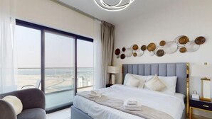 Habitación de hotel moderna con una cama grande, zona de estar y vistas a la ciudad.