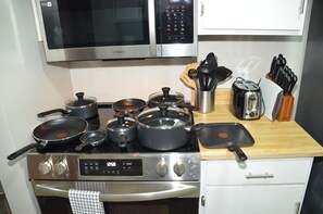 A kitchen with a microwave, stove, and various pots and pans. - Enchanting Oasis - Centrally located! Quiet, great TDY spot, family friendly. (Enterprise)