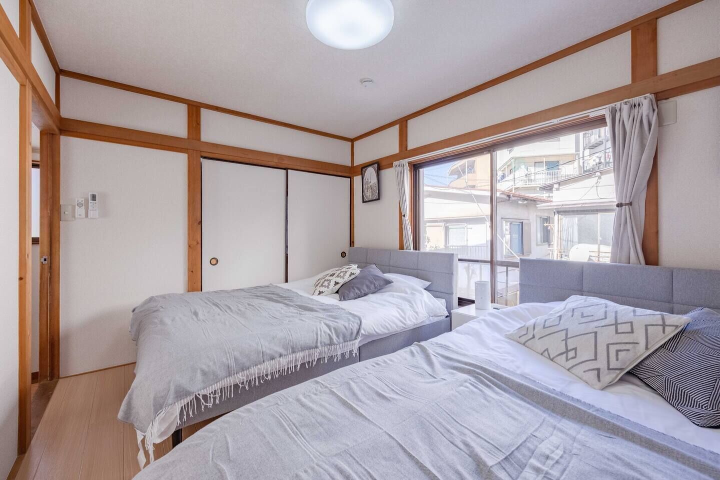 Una habitación con dos camas, paneles de madera, un ventanal con vistas y una lámpara en el techo.