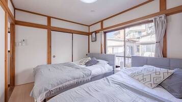 Una habitación con dos camas, paneles de madera, un ventanal con vistas y una lámpara en el techo.