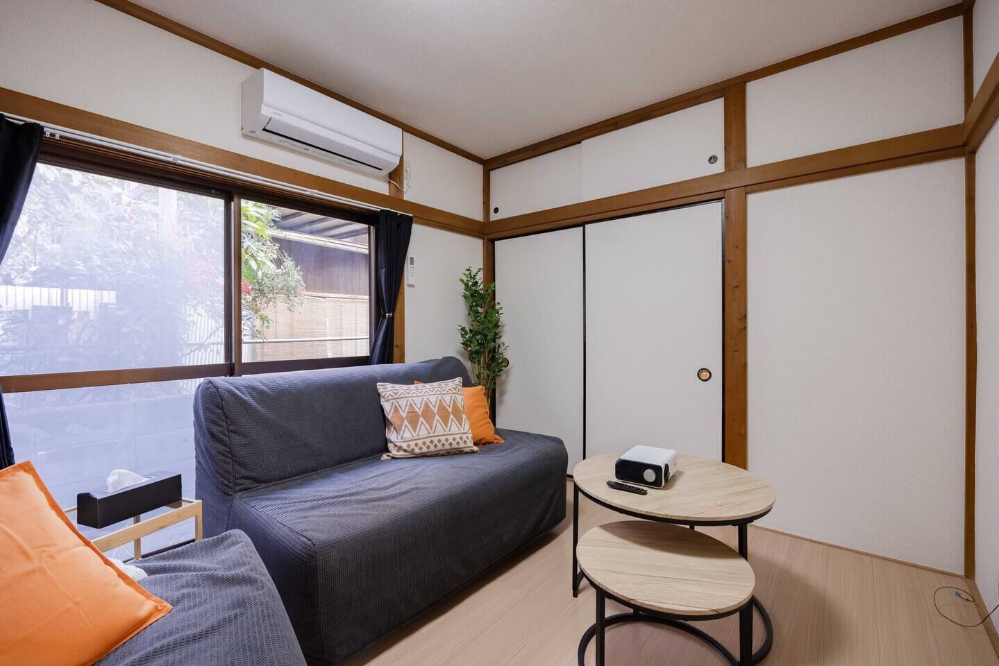 A compact room with a sofa, a small table, and a potted plant.