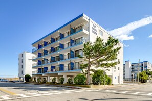 A multi-story hotel with balconies, a clear sky, and a tree in the foreground. - Exquisite Ocean View Condo with Pool (Ocean City)