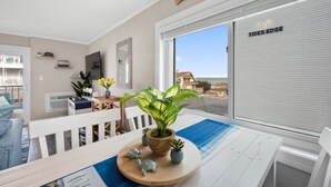 Une chambre moderne avec une grande fenêtre, une table en bois surmontée d’un tapis bleu, une plante en pot et une petite figurine de tortue.