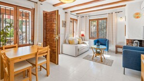 A spacious living room with a wooden dining table, a blue sofa, and a white couch. - El Rinconcito by Interhome (Moraira)