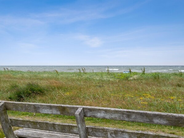 A wooden bench overlooking a grassy area with a view of the ocean.