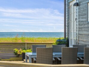 A wooden building with a view of the ocean. There are outdoor tables and chairs.
