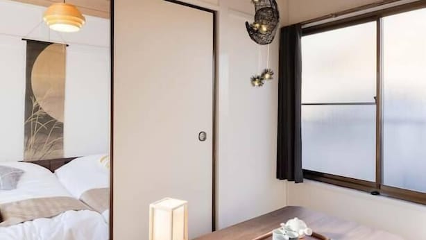 Une pièce avec un plafond en bois, un lit avec une literie blanche, une table avec un plateau, et une grande fenêtre donnant sur un beau paysage.
