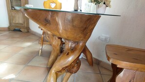 Een houten tafel met een glazen blad, een houten stoel en een betegelde vloer.