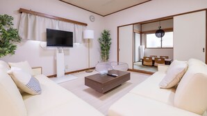 A modern living room with a flat-screen TV, a coffee table, two sofas, a lamp, and a large mirror.