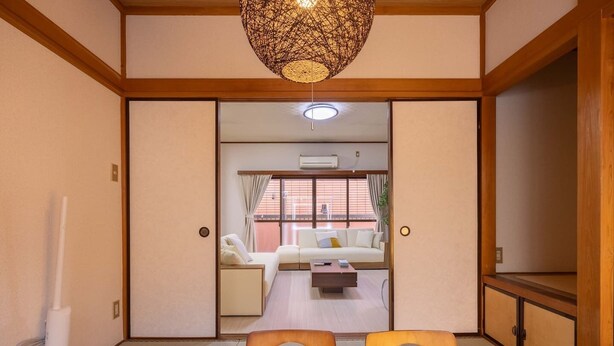 A traditional Japanese room with tatami flooring, a low wooden table, and a sofa.