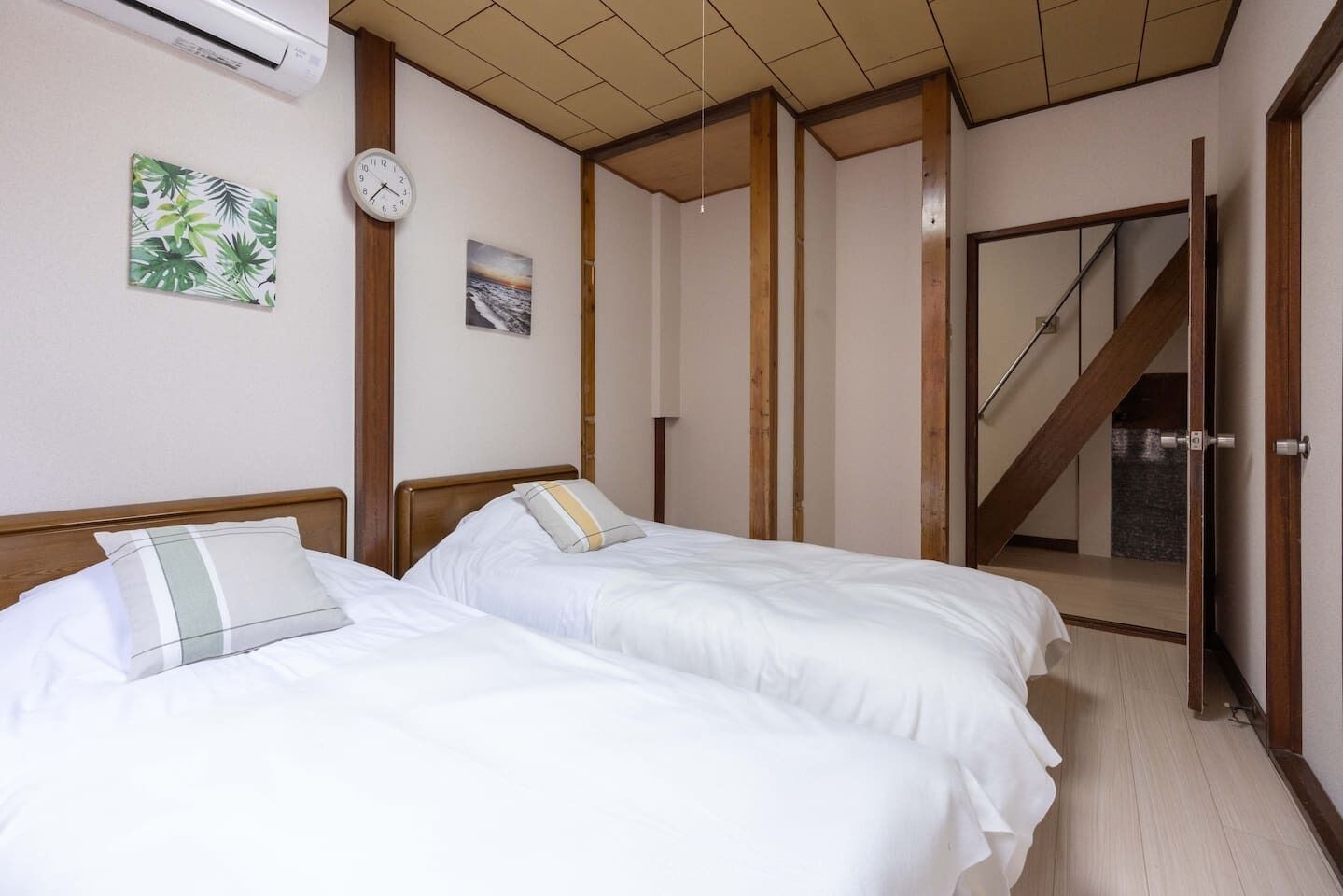 Quarto com duas camas, um relógio e uma escada.