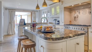 A kitchen with a large island, pendant lighting, and a view to the outside.