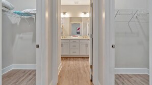 Un pasillo estrecho que conduce a un baño con lavamanos, espejo y toallero.