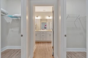 A narrow hallway leading to a bathroom with a sink, mirror, and towel rack.