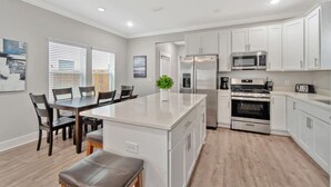 A modern kitchen with white cabinets, stainless steel appliances, and a central island. - Romana Hideaway-Main House, Downtown, New Listing! (Pensacola)