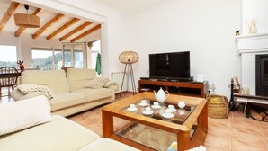 Una sala de estar amplia con un sofá, una mesa de centro con juegos de té, un televisor y una chimenea.