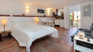 Una habitación de hotel con una cama grande, un pequeño rincón americano, una mesa de comedor y un sofá.