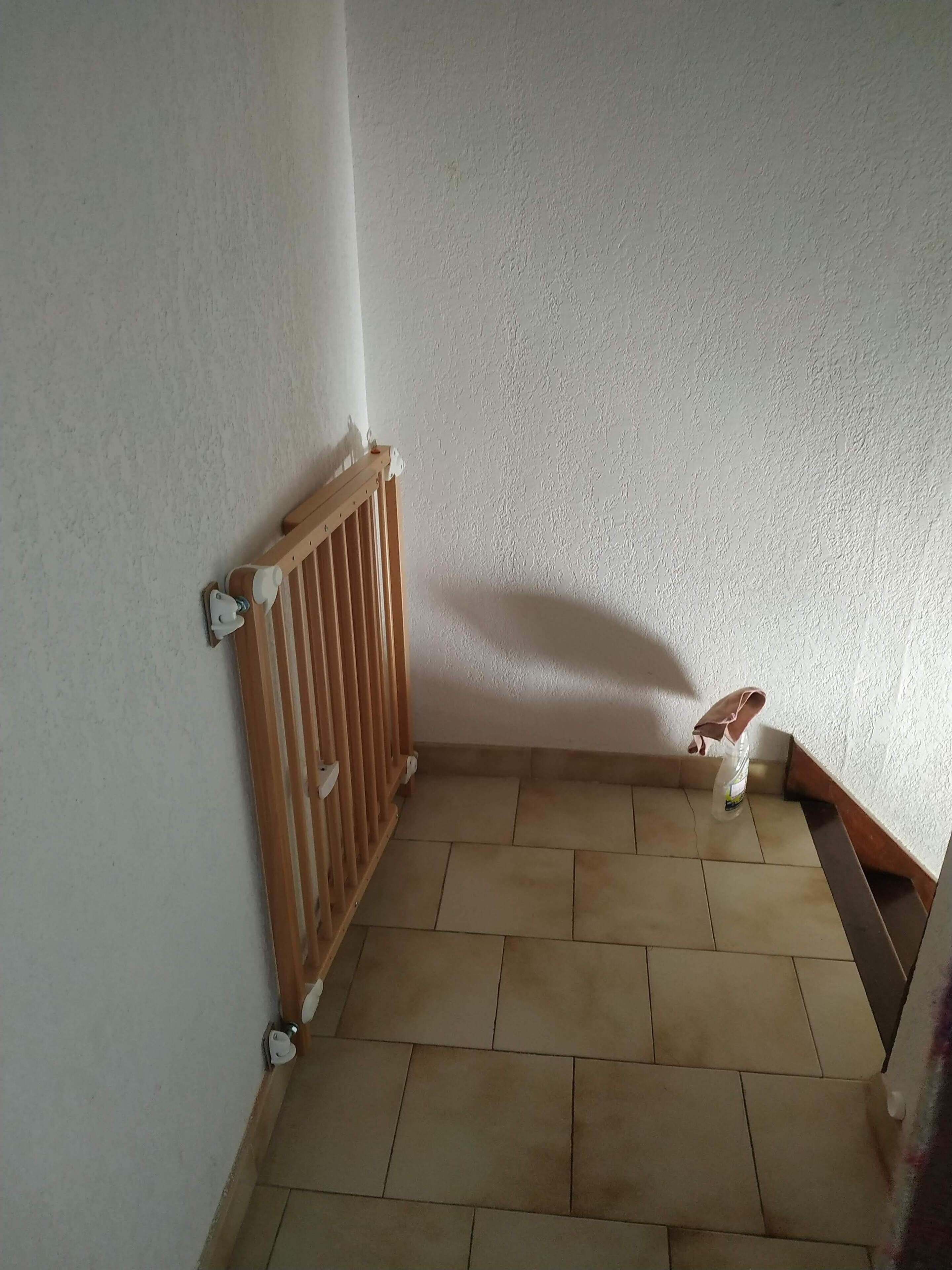 Esquina de una habitación con un radiador, piso de baldosas y zócalo de madera.