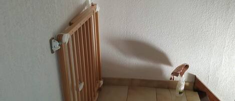 Esquina de una habitación con un radiador, piso de baldosas y zócalo de madera.