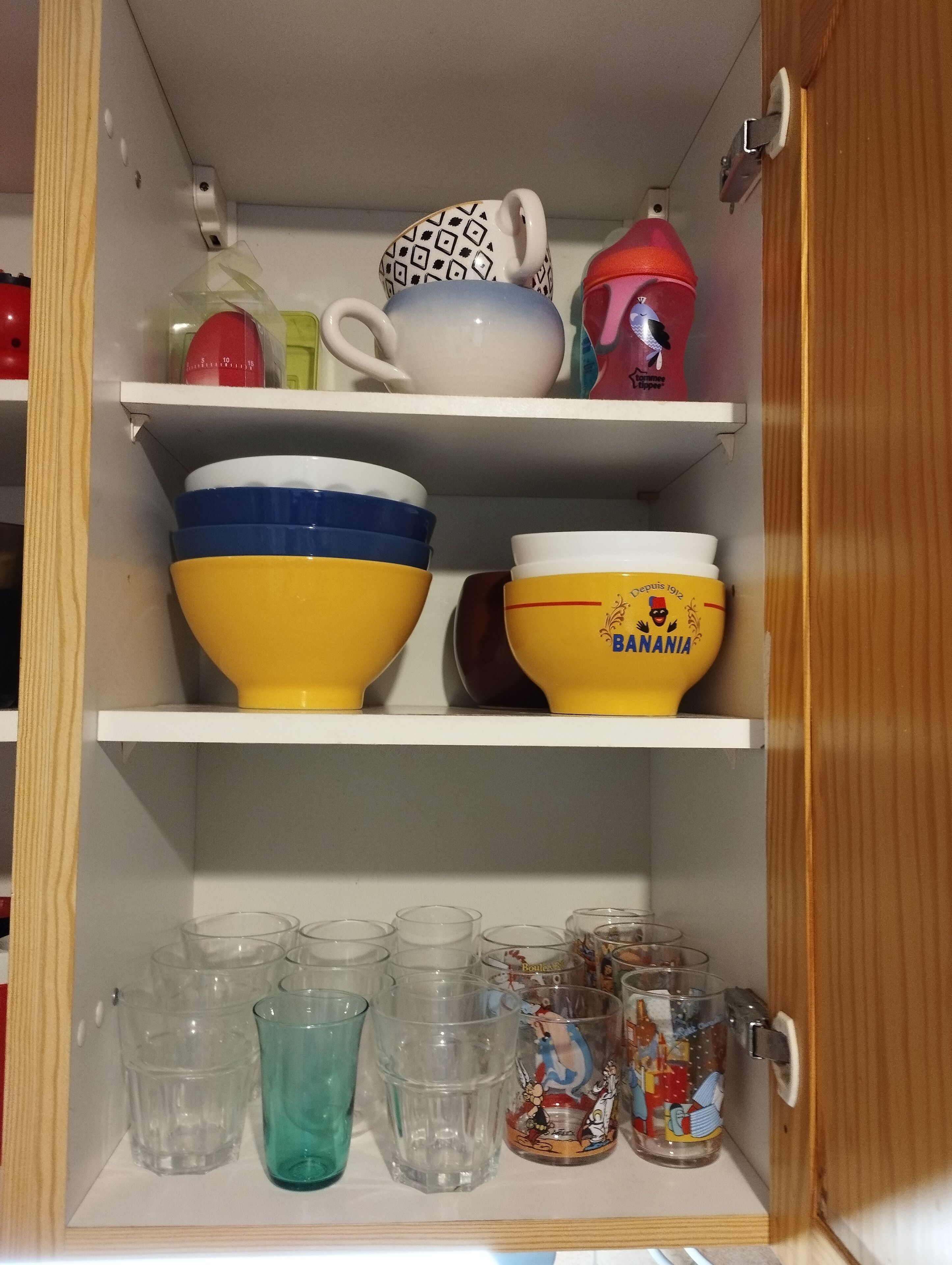A kitchen cabinet with shelves holding various kitchenware items.