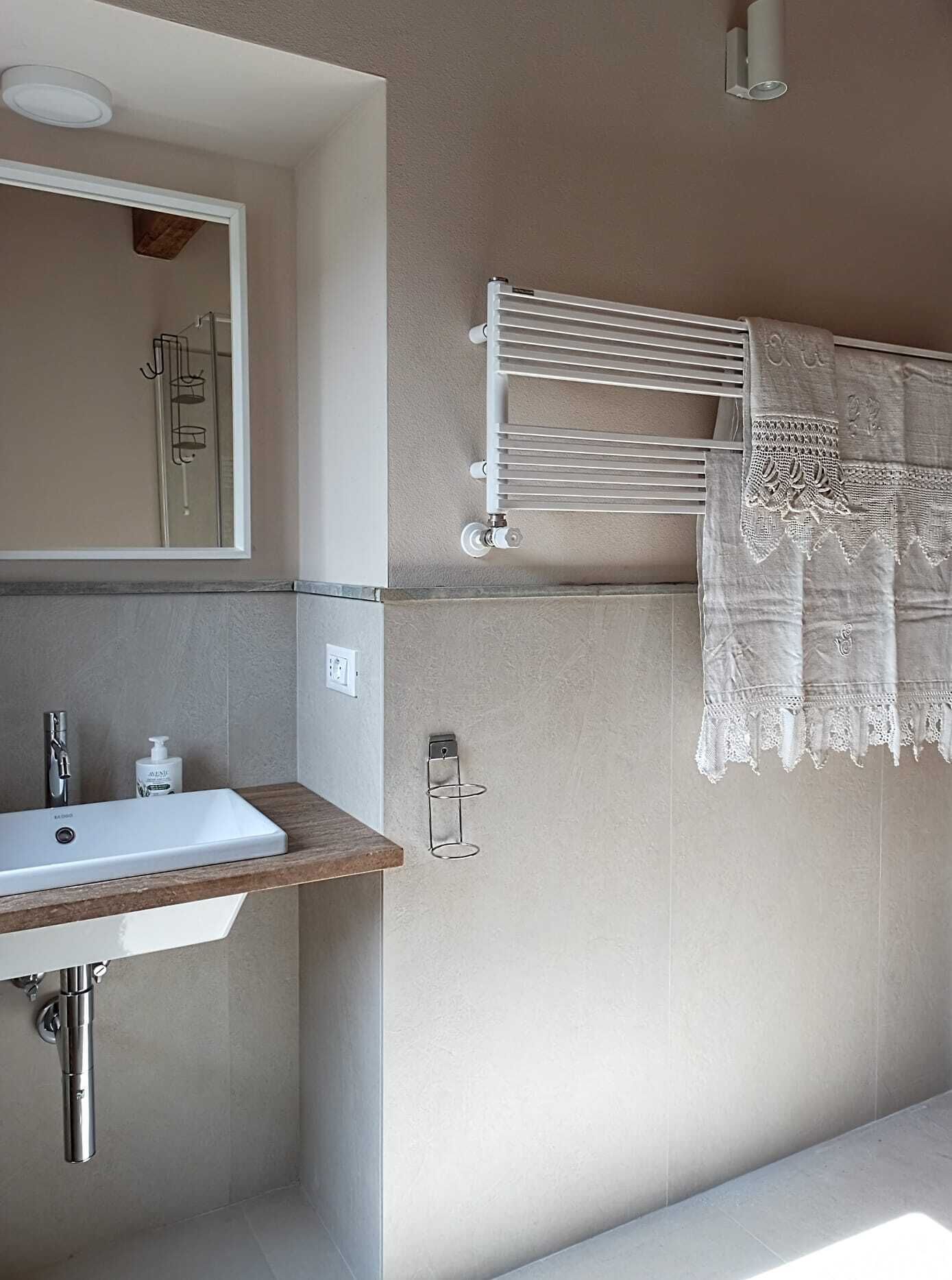 A bathroom with a white sink, a mirror, a towel rack, and a towel hanging on it.