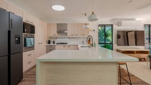 Una cocina moderna con una isla grande, electrodomésticos integrados y vistas al exterior.