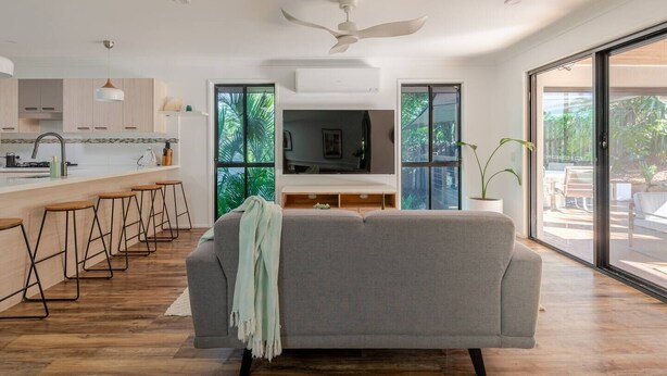 Una cocina moderna con barra, un sofá gris y ventanas amplias.