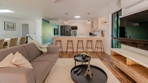 Una sala de estar moderna con un sofá, una mesa de centro con una maqueta de la Torre Eiffel, y un  área de cocina con una barra.
