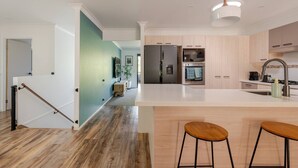 Una cocina moderna con una isla central, electrodomésticos de acero inoxidable y suelo de madera.