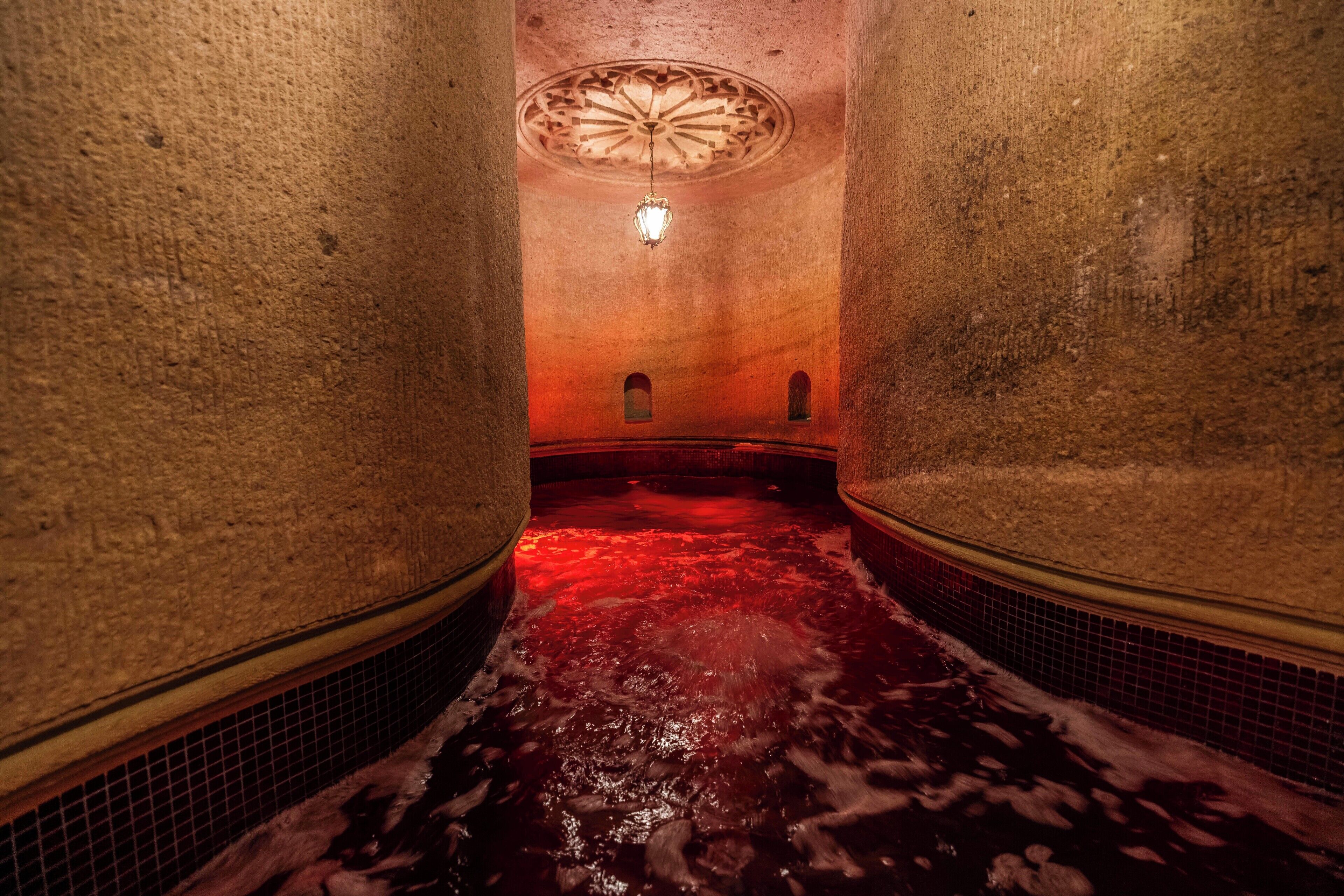 A narrow, dimly lit corridor with a red-lit floor, leading to a circular ceiling feature.
