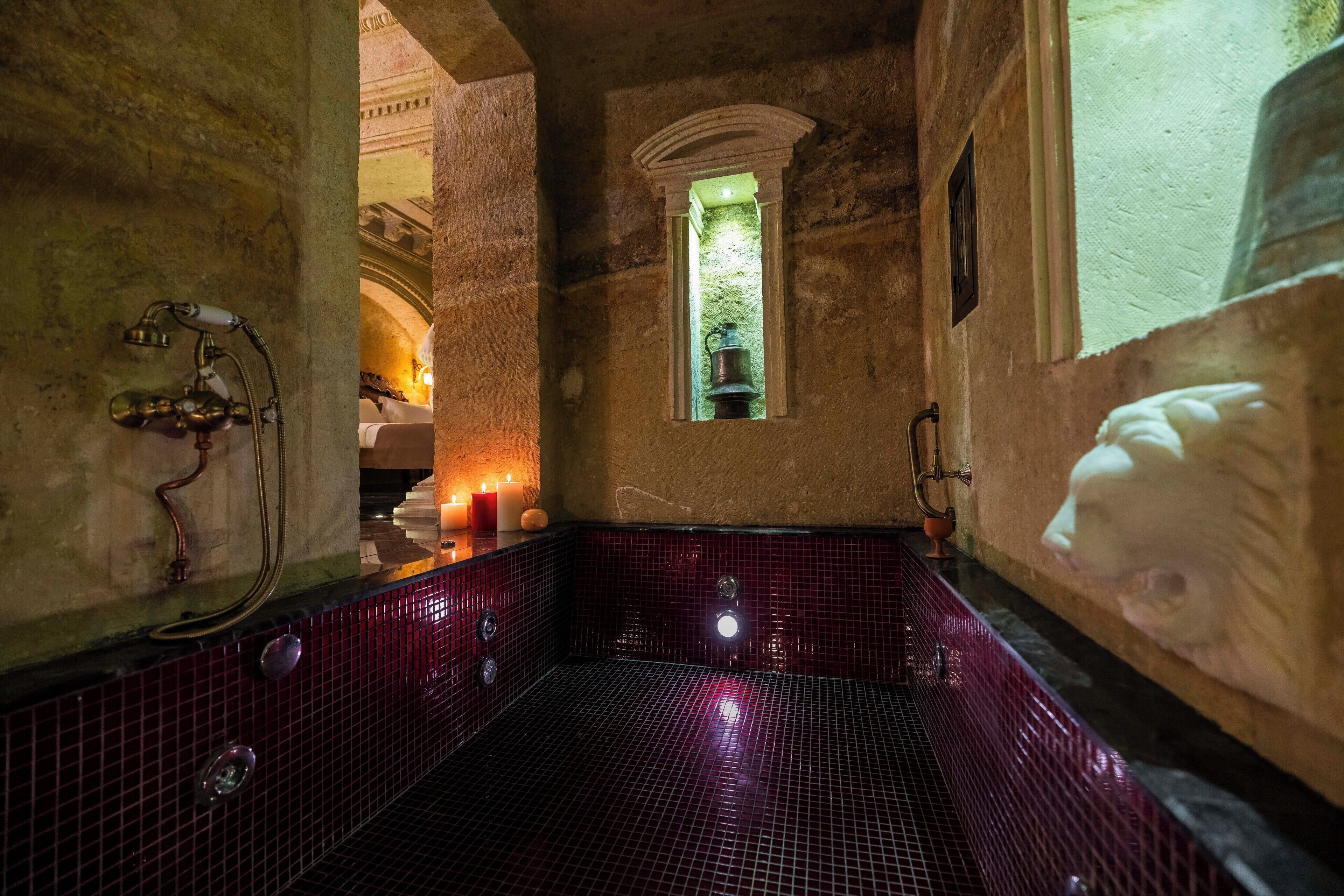 Une salle de bain historique avec un sol carrelé, une petite fenêtre et une baignoire.