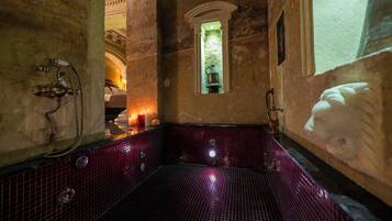 Une salle de bain historique avec un sol carrelé, une petite fenêtre et une baignoire.